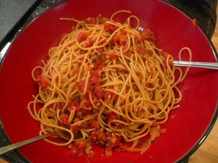 The cooked spaghetti is combined with the sauce.