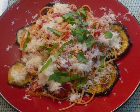 The spaghetti and sauce are served on the eggplant slices and coverd in grated chees and chopped herbs.